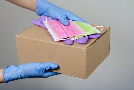 Hands with  surgical gloves  of a woman or man holding   gift boxes  package  ,  surgical gloves   and  protective face mask   .  Protective measures for the distribution of online shopping  during the covid-19 pandemic .の写真素材