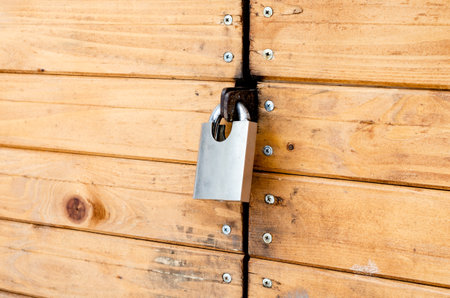Closed padlock on a painted brown pine wooden doorの写真素材