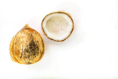 a pealed and cracked coconut on plain white background
