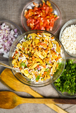 top view of famous indian snack bhel with ingredients arranged around it with copy space
