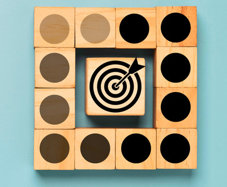A central wooden block displays a target with an arrow, surrounded by other blocks with circular patterns of varying shades.の写真素材