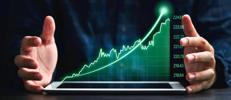 A tablet screen shows a bright green line graph with a strong upward trend, framed by two hands.の写真素材