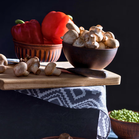 A still life composition featuring a red bell pepper, mushrooms, and green peas, suggesting preparation for a meal.の写真素材
