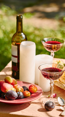 A romantic outdoor setting with wine, fruit, and candles on a table, perfect for a summer evening.の写真素材