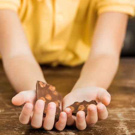 Close-up of a child's cupped hands holding dark soil and small seeds, ready for planting or gardening.の写真素材