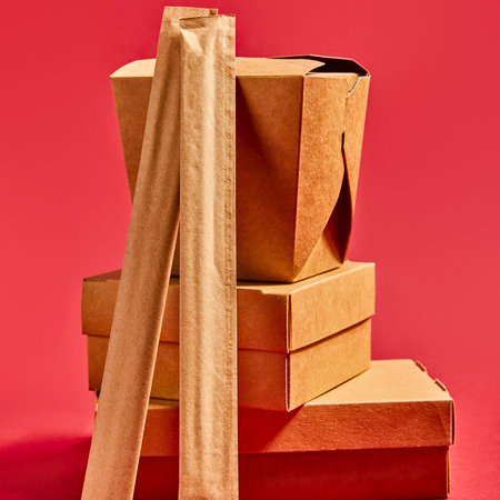 A close-up shot shows a stack of brown cardboard boxes, all set against a vibrant red backdrop.の写真素材