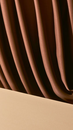 A detailed, abstract view of rich brown fabric with deep folds, contrasting with a smooth, light-colored surface below.の写真素材