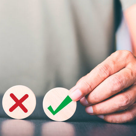 A person's hand hovers over wooden circles with a red cross and a green checkmark, symbolizing a choice or decision.の写真素材