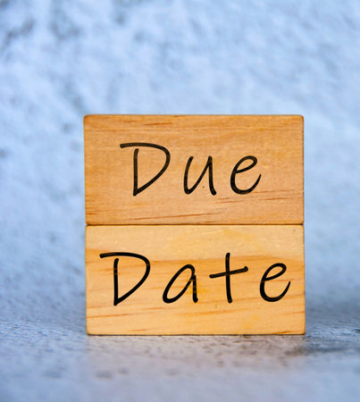 Two wooden blocks stacked vertically, with the words 'Due' and 'Date' written in black cursive on a textured background.の写真素材