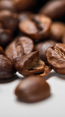 A detailed macro photograph showcasing the rich texture and deep brown color of numerous roasted coffee beans, artfully blurred in the background.の写真素材