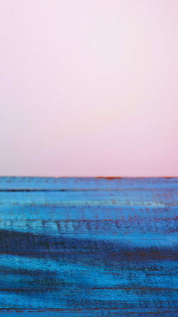 A minimalist abstract painting depicting a vast expanse of blue ocean meeting a soft pink sky at the horizon.の写真素材