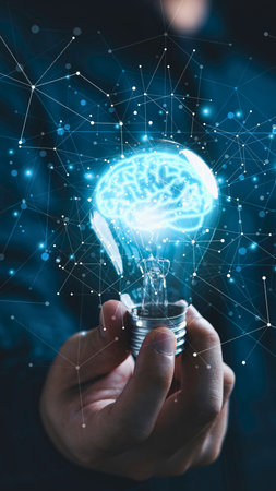 A hand holds a lightbulb containing a glowing brain, surrounded by a digital network and abstract blue lights.の写真素材