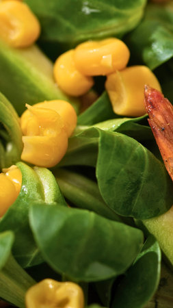 A vibrant, close-up view of fresh green spinach leaves mixed with bright yellow bell pepper pieces, suggesting a healthy and delicious salad.の写真素材