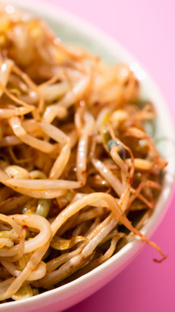A detailed, close-up view of a bowl filled with golden-brown, crispy fried noodles, set against a soft pink backdrop.の写真素材