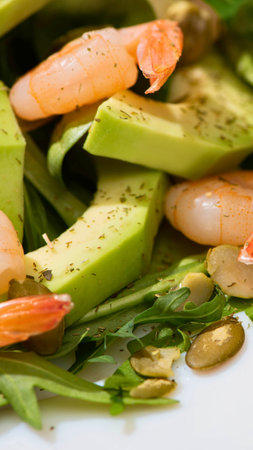 A close-up view of a vibrant salad featuring succulent shrimp, creamy avocado slices, and fresh green leaves.の写真素材