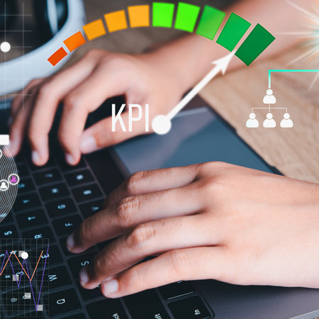 A close-up of hands typing on a laptop keyboard, with a digital KPI dashboard showing progress and performance metrics.の写真素材