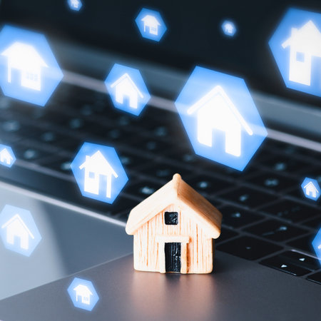 A miniature house sits on a laptop keyboard surrounded by glowing hexagonal icons of houses, symbolizing online property search and digital real estate.の写真素材