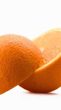A detailed view of the textured rind of an orange, with a slice of the juicy fruit visible behind it.の写真素材