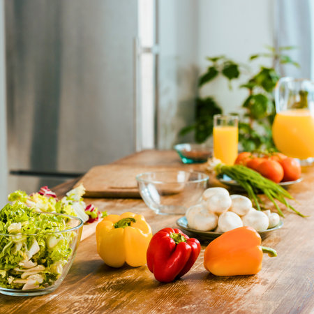 A vibrant assortment of fresh vegetables and glasses of orange juice are arranged on a kitchen counter, ready for meal preparation.の写真素材
