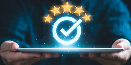 Hands hold a tablet displaying a glowing checkmark within a circle, surrounded by five stars, symbolizing excellent quality and customer approval.の写真素材