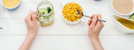 Overhead view of hands preparing a healthy meal with fresh vegetables and grains, showcasing a vibrant and nutritious culinary experience.の写真素材