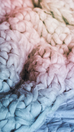 A close-up view of chunky, hand-knitted yarn in soft pastel colors, creating a cozy and inviting texture.の写真素材