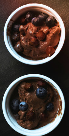 Two oval white bowls filled with a dark, rich, textured food, possibly a stew or dessert, against a dark background.の写真素材