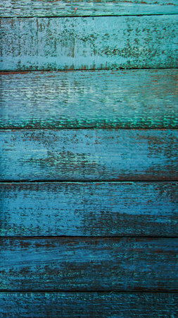 A close-up view of horizontal wooden planks with a distressed, weathered finish in shades of teal and deep blue.の写真素材