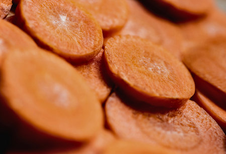 A macro shot of thinly sliced carrots revealing their intricate circular patterns and vibrant orange hue.の写真素材