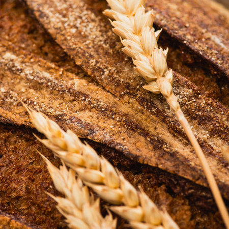 A detailed macro shot of a rustic loaf of bread, adorned with delicate stalks of ripe wheat.の写真素材