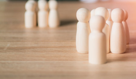 A group of wooden peg figures stands together on a wooden surface, symbolizing community, connection, and social interaction.の写真素材