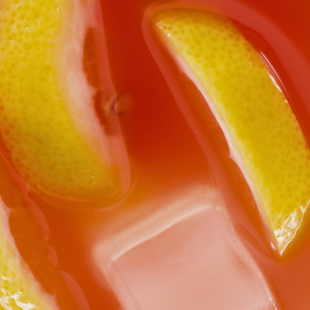 Close-up of bright yellow citrus slices submerged in a translucent, warm-toned liquid, suggesting a refreshing drink.の写真素材