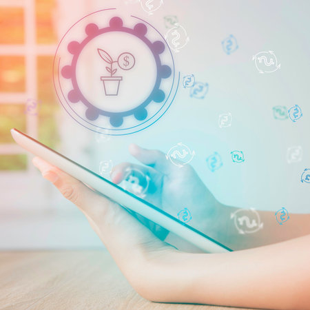 A person uses a tablet with digital graphics overlayed, symbolizing growth, innovation, and...