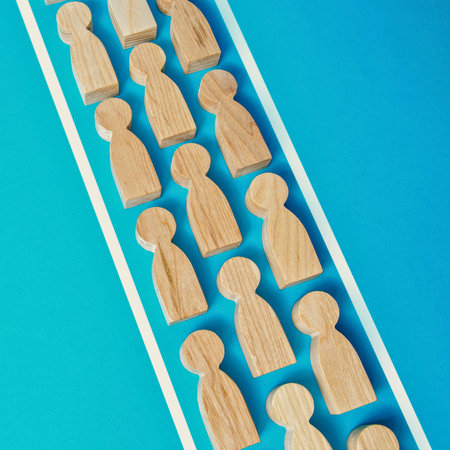 A collection of small, light-colored wooden peg dolls arranged in parallel rows on a vibrant blue surface.の写真素材