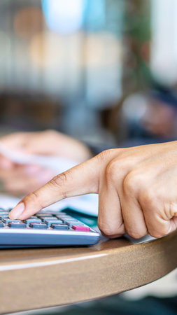 A person's finger presses a button on a calculator, suggesting financial planning or accounting tasks.の写真素材