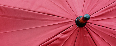 A detailed, abstract view of the inside of a bright red umbrella, showing the fabric texture and the central pole.の写真素材