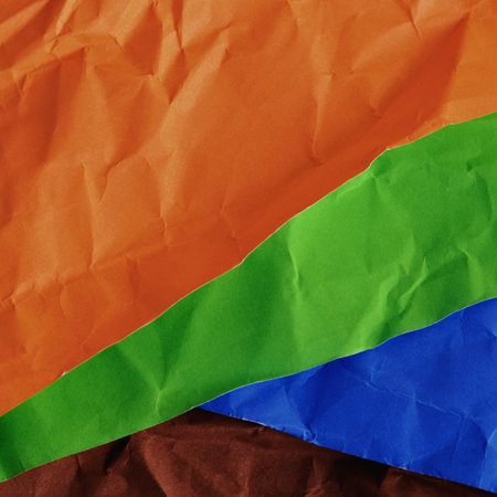 A close-up view of layered, crinkled fabric showcasing bold orange, green, blue, and brown hues in an abstract arrangement.の写真素材