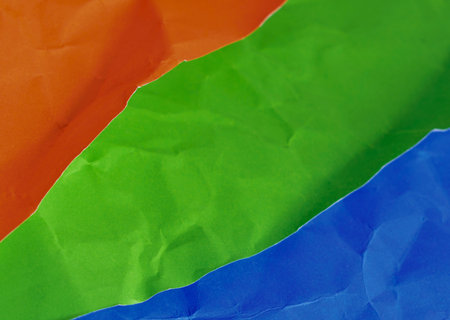 A close-up abstract view of three distinct, brightly colored fabric layers arranged diagonally with visible texture and folds.の写真素材