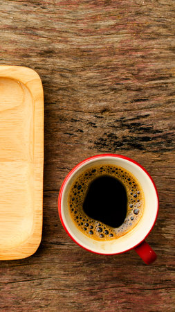 A halved passion fruit sits next to a light wooden plate on a rustic wooden surface.の写真素材