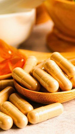 A collection of light brown, oval-shaped capsules are artfully arranged on a wooden spoon, with a softly blurred background.の写真素材