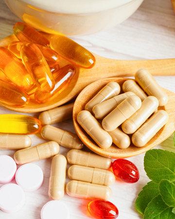 A close-up of various pills capsules and supplements including softgels and tablets with mint leaves for a healthy lifestyle.の写真素材