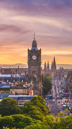 A panoramic view of Edinburgh's historic skyline at sunset, featuring the prominent clock tower and distant castle.の写真素材