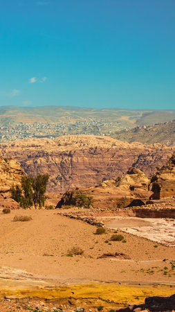 An expansive desert panorama stretches towards the horizon under a bright, cloudless blue sky. The terrain features sandy plains and rocky outcrops.の写真素材
