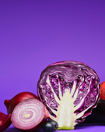 A halved red cabbage and sliced red onion are artfully arranged on a vibrant purple surface, showcasing their fresh textures and colors.の写真素材