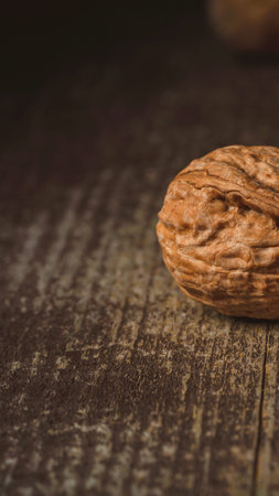 A single, textured walnut rests on a dark, weathered wooden table, bathed in soft light.の写真素材