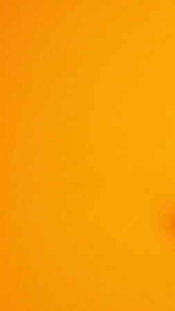 A warm, abstract background featuring a smooth gradient from deep orange to bright yellow, with a subtle, almost pixelated texture.の写真素材