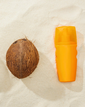 A whole coconut and a bright orange cylindrical container are placed side by side on a light,...