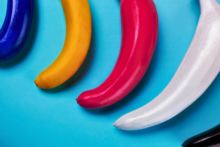 A vibrant close-up shot features the curved handles of tools or objects in bright blue, yellow, red, and white, set against a solid blue surface.の写真素材