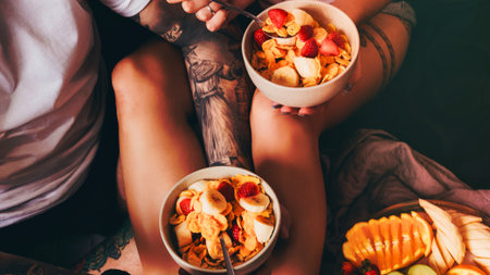 A close-up overhead view of two white bowls filled with food and a charcuterie board with sliced fruit.の写真素材
