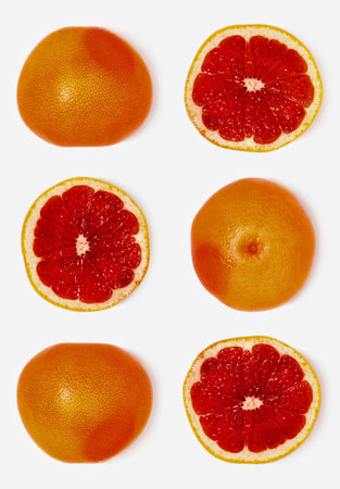 A top down view of three whole grapefruits and three sliced grapefruits arranged in a grid on a...